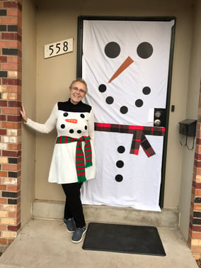 Lois Brady lleva ropa navideña de muñeco de nieve mientras está delante de una puerta decorada igual que la ropa que lleva puesta