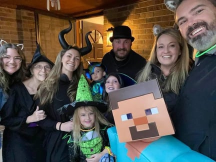 Lois Brady and her loved ones are dressed in Halloween costumes, posing for a group photo on a front porch