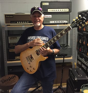 Middle aged man holds an electric guitar in his hands