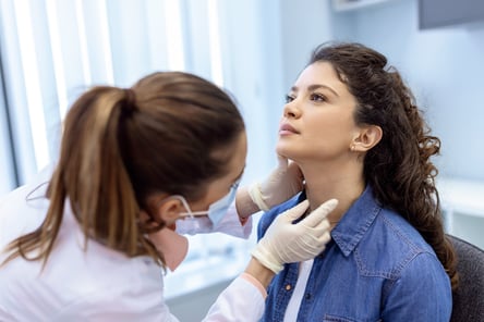 A doctor feels a woman’s neck for signs of swelling