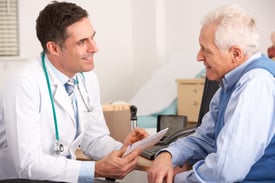 A patient speaks with his doctor in an exam room