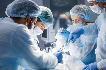 A surgical team dressed in personal protective equipment operates on a patient