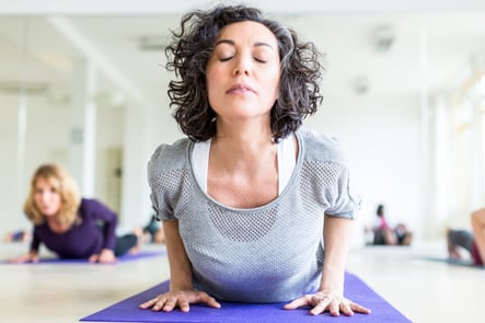 A woman exercises on a purple yoga mat