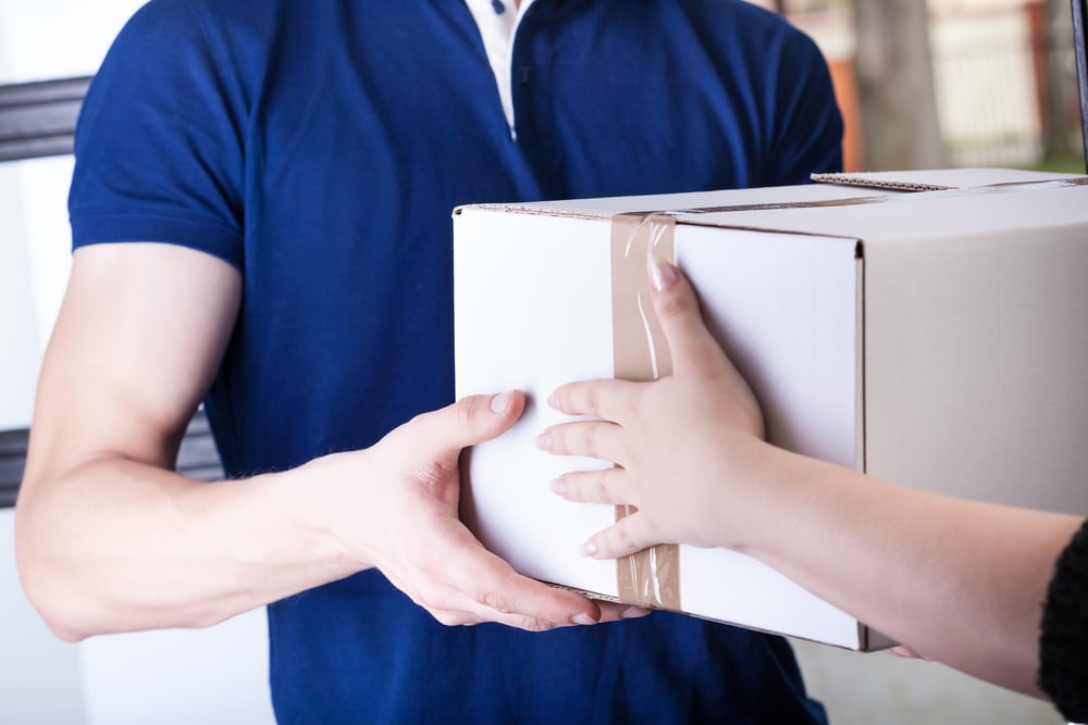A close-up of a person accepting a package from a courier delivering it.