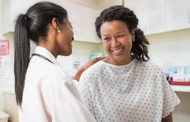 Una doctora habla con su paciente, que lleva una bata de hospital