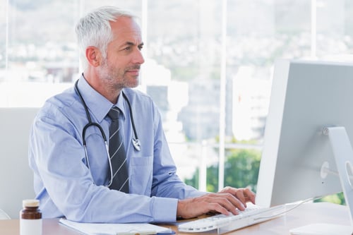 Médico escribiendo en su ordenador en la oficina