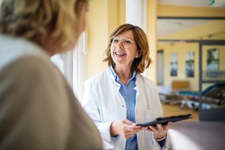 A doctor speaks with her patient while holding a tablet computer