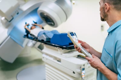 Doctor working while woman is undergoing radiation therapy for cancer