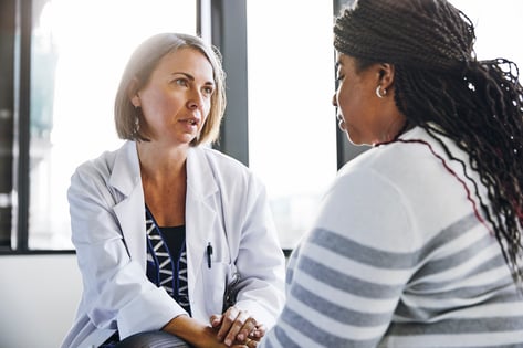 Mature doctor talking to young woman in hospital