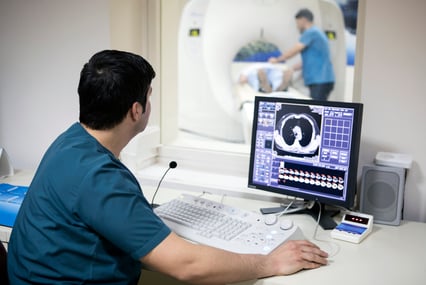 A healthcare provider watches the progress of an imaging scan on his computer monitor