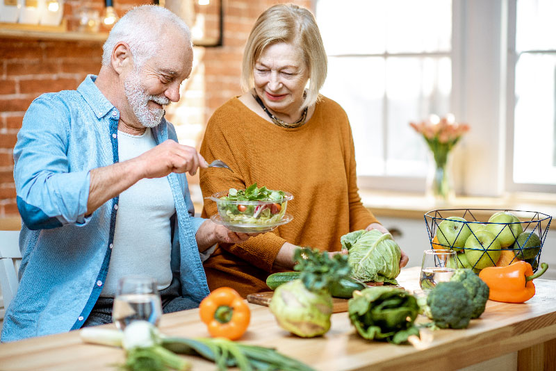 Pareja de ancianos feliz y saludable haciendo una ensalada