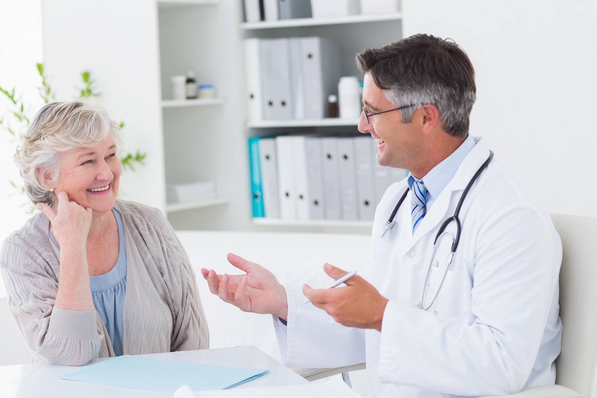 A smiling doctor and patient talk in an office setting.