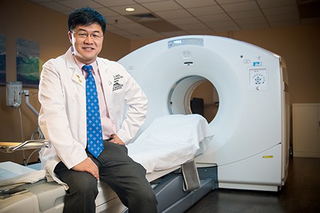 Dr. Eric Liu sitting by CT scanner