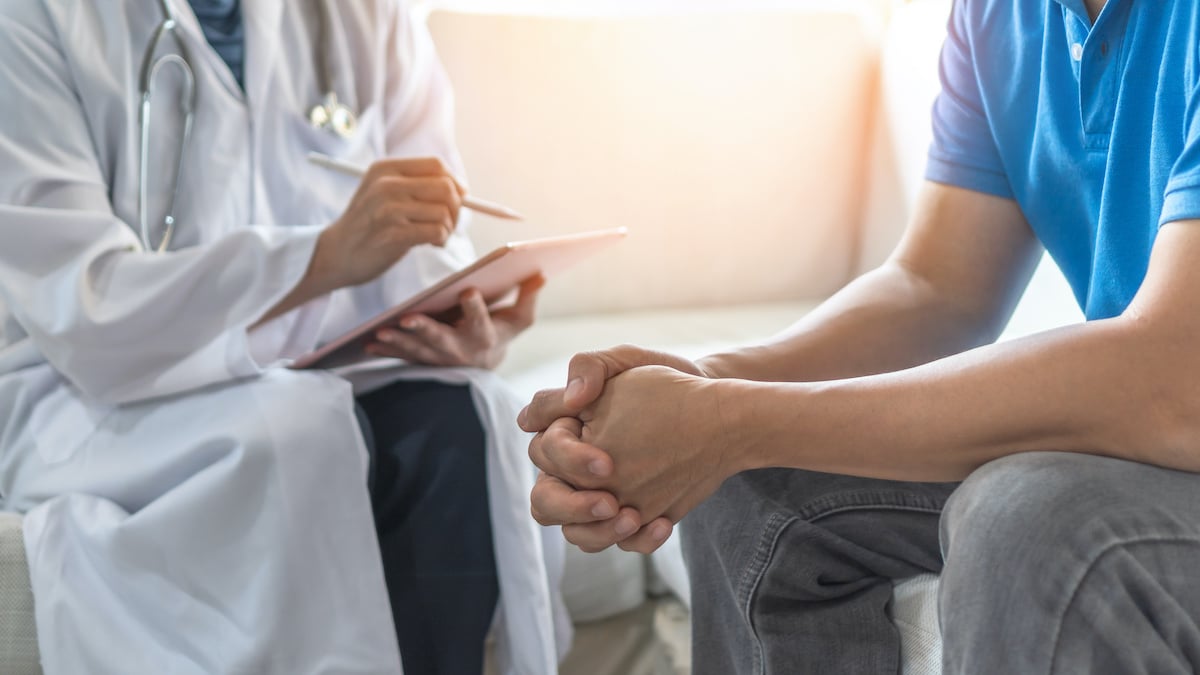Close-up of a doctor asking a patient questions and taking notes.