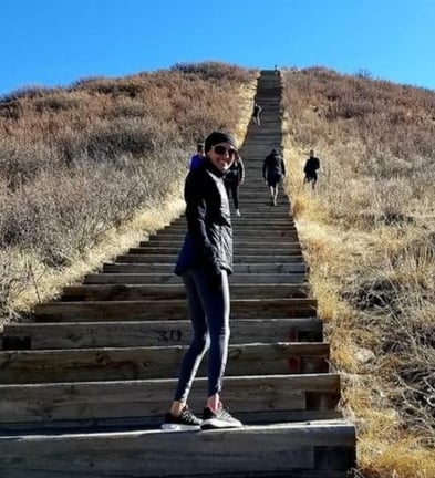 Kathryn Gray mira hacia atrás mientras sube las escaleras de madera de un sendero en la colina