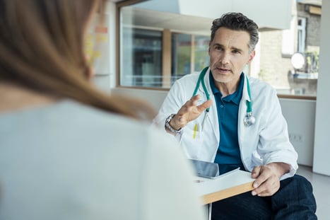 Un sanitario blanco habla con una paciente.