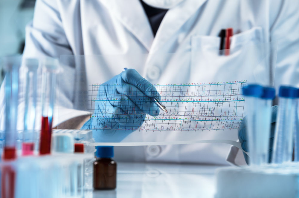 A close-up photo of a person dressed in a lab coat inspecting test results. They are wearing blue gloves and are surrounded by test tubes.