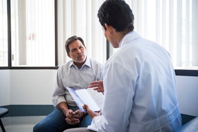 Vista trasera de un médico hablando con un paciente mayor