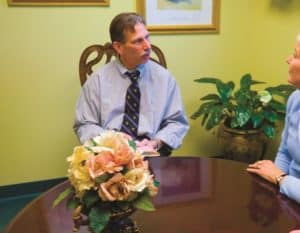 Two people sit at a table speaking to each other.