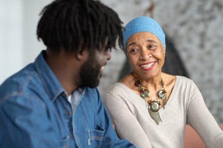 Mujer adulta con cáncer sonriendo y hablando con un hombre adulto