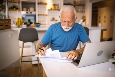 Senior man using a laptop to pay his bills online at home