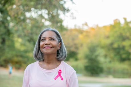 Женщина средних лет носит розовую ленту для осведомления о раке груди