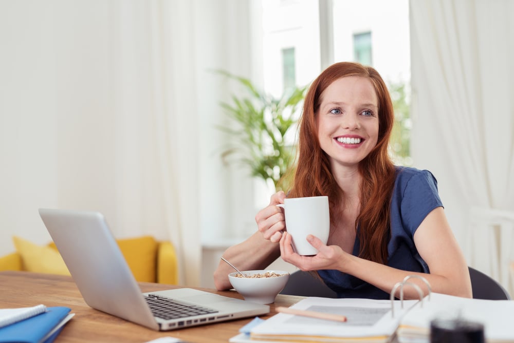 Thoughtful Young Woman Having her Breakfast at her Home Office, Showing Happy Facial Expression.