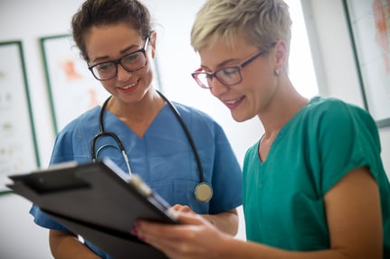 Two female medical professionals review a patient’s chart