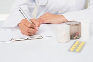 Doctor writing on clipboard the prescriptions in medical office
