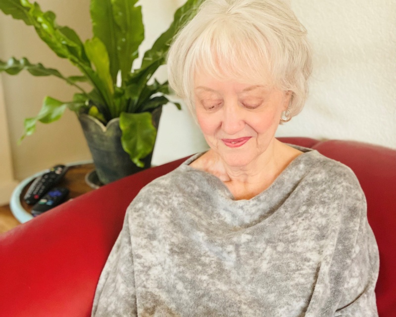 A woman sits on a red chair and looks down at something in her lap.