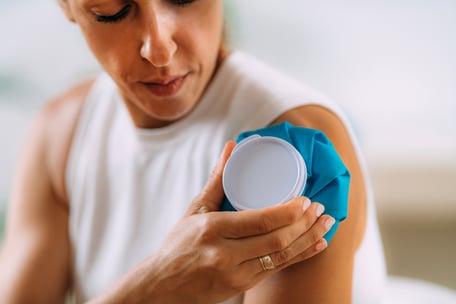 A woman applies an ice pack to her shoulder