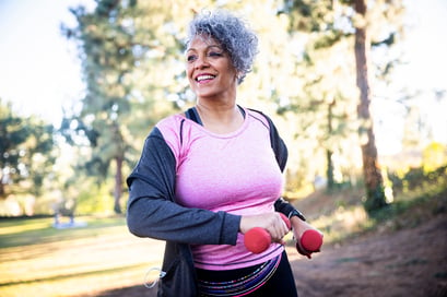 Woman holding weights while jogging outdoors