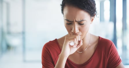 A woman suppresses a cough