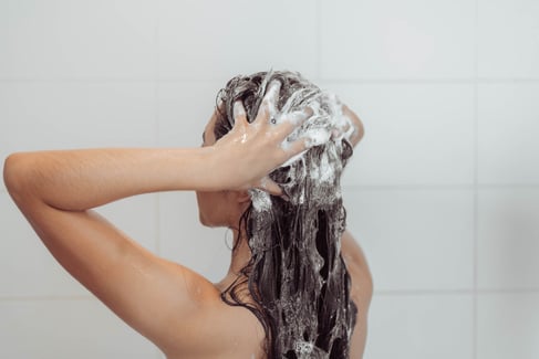 Young woman washing hair in shower