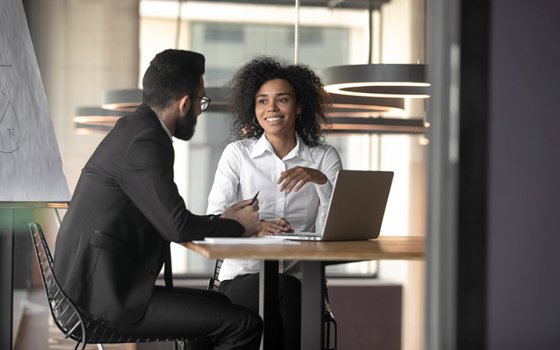people speaking office at a table with a laptop